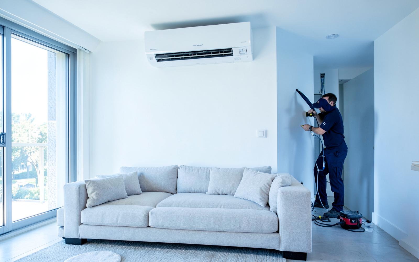 Technicien CLIMARAUJO installant un climatiseur mural dans un salon